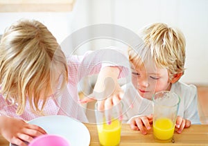 Children, juice and curious in home in the morning with food, kids and glass ready for eating. Family, dinner table and