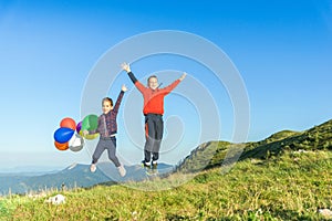 Children jump with balloons in hand that sway in the wind photo