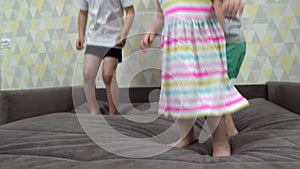 Children jump on the bed, close-up shooting of jumping feet