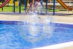 Children jump, swim and play in the pool on a beautiful sunny summer day.