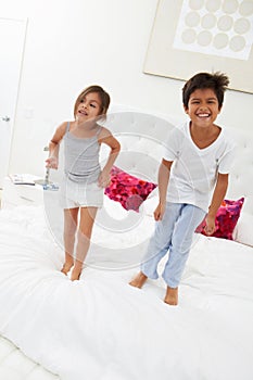 Children Jumping On Bed In Pajamas Together