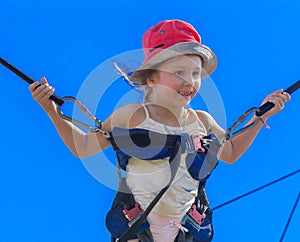 Children jumping on a trampoline with rubber ropes against the b