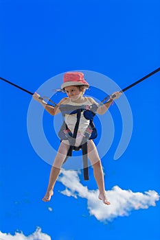 Children jumping on a trampoline with rubber ropes against the b