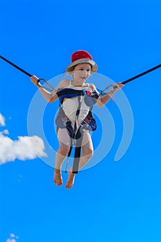 Children jumping on a trampoline with rubber ropes against the b