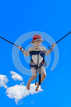 Children jumping on a trampoline with rubber ropes against the b