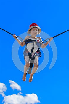 Children jumping on a trampoline with rubber ropes against the b