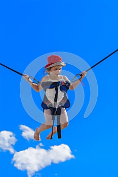 Children jumping on a trampoline with rubber ropes against the b