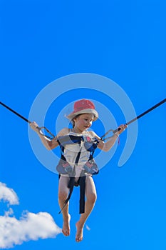 Children jumping on a trampoline with rubber ropes against the b