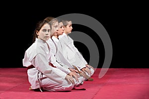 Children in kimono sitting on tatami on martial arts seminar. Selective focus