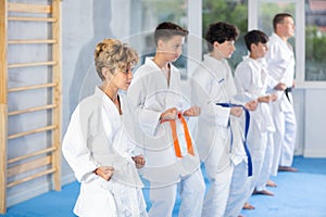 Children in kimono standing in line on tatami and practicing blows in gym