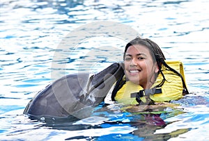 Children kissing dolphin in pool