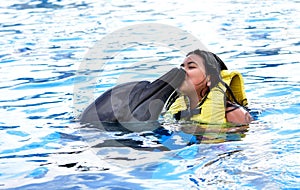 Children kissing dolphin in pool