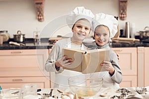 Children in kitchen. Brother and sister are reading cookbook while cooking.