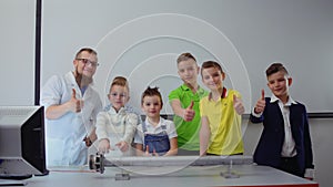 Children and laboratory assistant shows thumbs up to camera