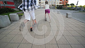 Children learn to ride scooter on sunny summer day. Kids play outdoors with scooters. active leisure and outdoor sport