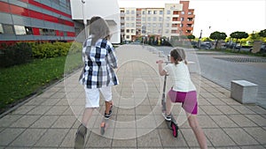 Children Learn To Ride Scooter On Sunny Summer Day. Kids Play Outdoors With Scooters. Active Leisure and Outdoor Sport