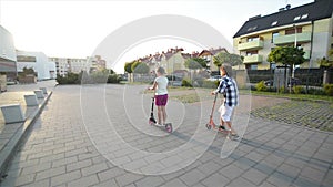 Children Learn To Ride Scooter On Sunny Summer Day. Kids Play Outdoors With Scooters. Active Leisure and Outdoor Sport