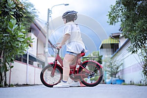 Children learning to drive a bicycle on a driveway outside