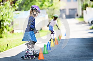 Children learning to roller skate on the road with cones