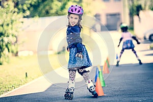 Children learning to roller skate on the road with cones