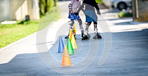 Children learning to roller skate on the road with cones.