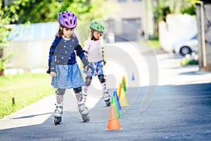 Children learning to roller skate on the road with cones.