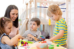 Children learning to work colorful play dough in nursery, kindergarten or day care center