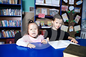 Children in library happy reading book. Little girl and boy learning