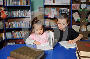 Children in library reading interesting book. Little girl and boy learning