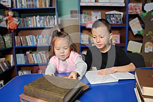 Children in library reading interesting book. Little girl and boy learning