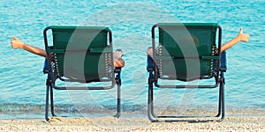 Children lie on chaise longue and look at the sea.