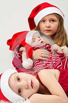 Children lie on fur in the hats of Santa Claus