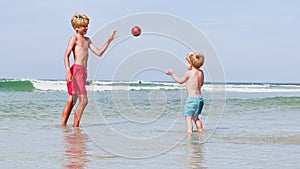 Children little boys and girl play with ball in sea at beach