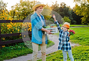 Children little girl holding mom a basket of fresh organic vegetables with the home garden.