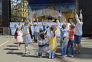 Children little girls boys playing game hands up, musicians playing music on a background. Ethno Fest. Kyiv, Ukraine