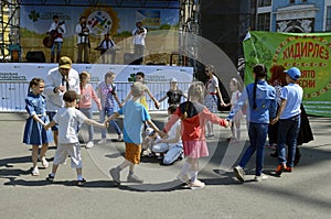 Children little girls boys playing game hands up, musicians playing music on a background. Ethno Fest. Kyiv, Ukraine