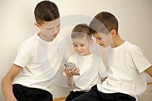 children look at phone with interest social networks look Three brothers t-shirts white background children's