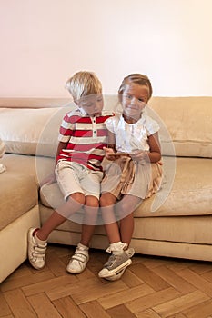 children look at smartphone screen. blond boy looks into phone to happy sister