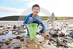 Children Looking In Rockpools On Winter Beach Vacation