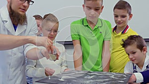 Children looks at dancing sand on chladni plate in laboratory