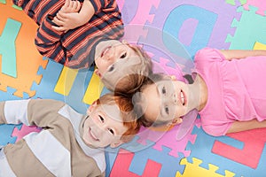 Children lying on backs on fun kids alphabet mat photo