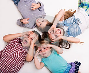 Children lying on the floor with hands imitating glasses