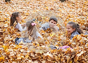 Children are lying and playing on fallen leaves in autumn city park