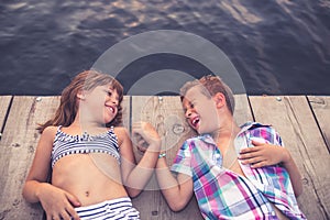 Children lying on the wooden pier and holding hands