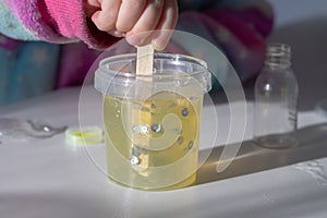 Children make slime themselves from glue and thickener, kids play with homemade yellow slime