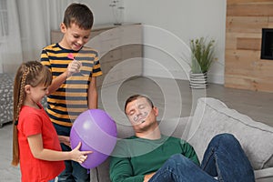 Children making balloon explosion joke for their father