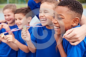 Children With Male Coach Showing Off Winners Medals On Sports Day