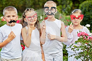 Children with masks on stiks stand together in photo