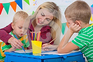 Children with mom and draw pictures in the kids room.