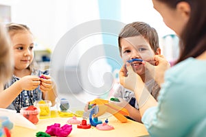 Children and mom or kindergartener make by hands playing with color dough. Kids show imagination and have fun with plasticine